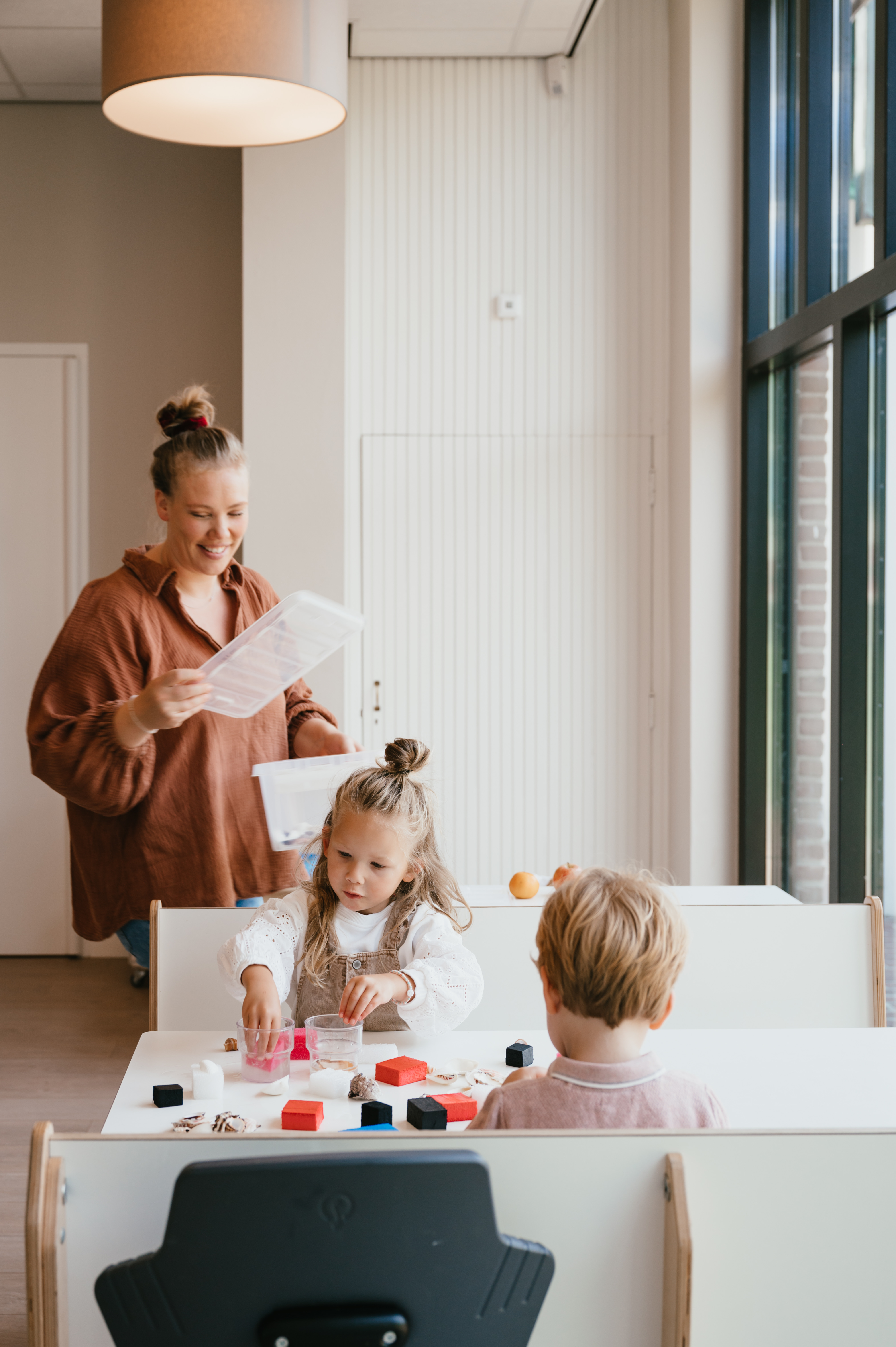 Pedagogisch Medewerker en kinderen knutselen op de kinderopvang